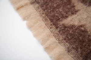 Macro shot of beige and brown star jacquard scarf featuring soft plush fringe details