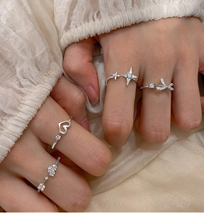 Detail of stacked silver rings with sparkling heart and star charms on hand
