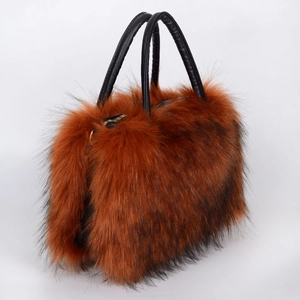 Detail of reddish-brown faux fur tote bag with black leather straps and gold zipper