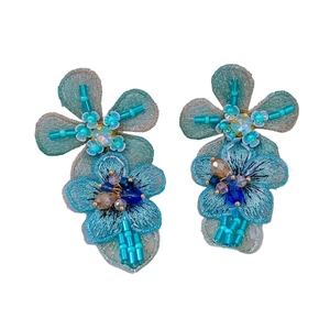 Blue knit flower earrings with sparkling rhinestones and beads on white background