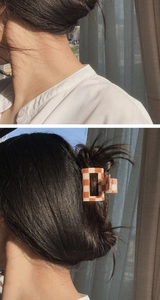 Detail of checkered hair claw clip in orange and white pattern on long hair