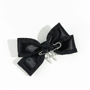 Detail of gothic black satin bow hair clip with silver safety pin and cross charms