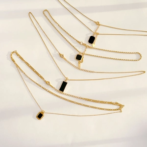 Minimalist gold necklace set with geometric black onyx pendants on a white background