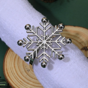 Detailed view of a silver snowflake napkin ring with rhinestones on a white linen napkin