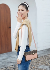 Outdoor shot showing pink and brown monogram small square bag worn by a model