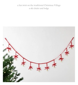 Christmas garland with red velvet bows and golden bells hanging on a red string