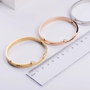 Close-up of three polished stainless steel spike bangles with ruler for size reference