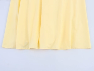 Détail de l'ourlet d'une robe d'été à rayures jaunes montrant la texture et le drapé du tissu
