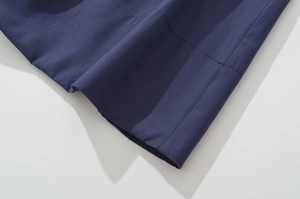 Detailed close-up of dark blue cotton fabric texture and clean hem stitching quality