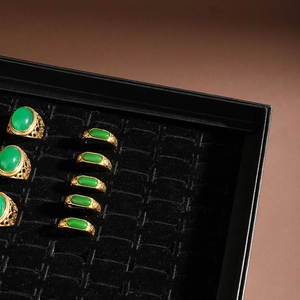 Macro detail of vintage gold rings with green emerald stones on black velvet display