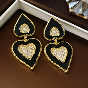 Makroaufnahme von Vintage-Herzohrringen mit schwarzer Emaille, Diamanten und Goldtextur