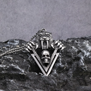 Saber-tooth tiger skull pendant in polished stainless steel on a dark rocky background