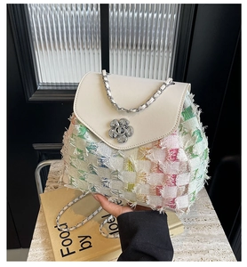 Close-up of white PU leather flap tweed bucket bag with floral metal clasp and silver chain