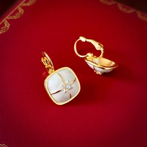 Detail of vintage square gold earrings with white enamel inlay and central zircon stone