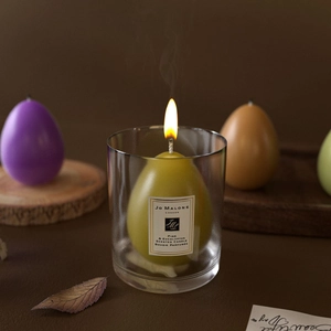 Egg-shaped pine and eucalyptus scented candles in glass jars with festive decor