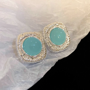 Vue macro de boucles d'oreilles carrées vintage argentées avec résine ronde bleu clair