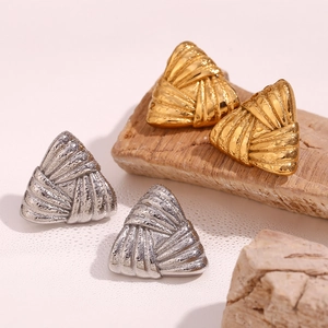 Macro shot of striped triangular stud earrings in gold and silver finishes on cork