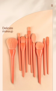 Close-up of 11-piece coral orange makeup brush set with soft bristles and matte handles