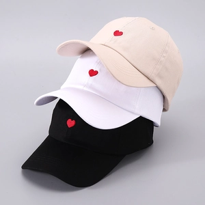 Detailed embroidery of red hearts on beige, white, and black cotton twill baseball caps
