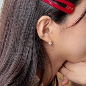 Close-up of minimalist freshwater pearl earring on ear showing size and golden finish