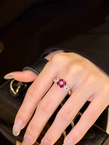 Close-up of floral ring with ruby-toned stones and diamonds worn by model