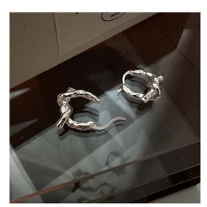 Macro shot showing S925 sterling silver hallmark and lava texture on knot hoop earrings