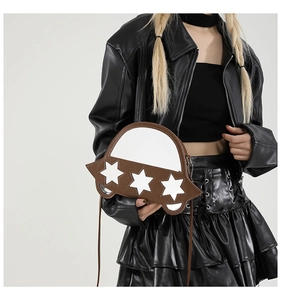 Détail d'un sac bandoulière marron et blanc en forme d'OVNI avec des étoiles sur mannequin