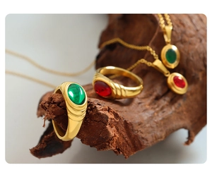 Artistic layout of vintage gold jewelry set with emerald and ruby gemstones on bark