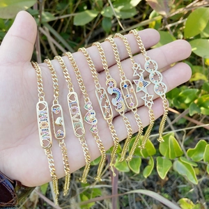 Gold finish bracelets with zircon stars, hearts, and LOVE charms worn by a hand outdoors