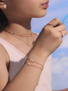 Detailed view of pink butterfly jewelry set worn on model against a blue sky background
