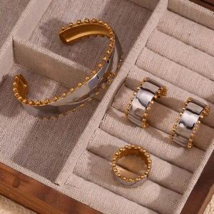 Macro shot of two-tone gold and silver jewelry set with bead edges in a wooden tray