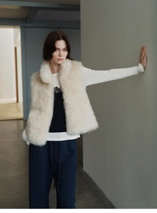 Detail of cream faux fur vest showing soft texture and layered autumn outfit design