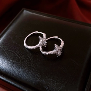 Macro shot of silver star zircon earrings on black leather and red silk fabric