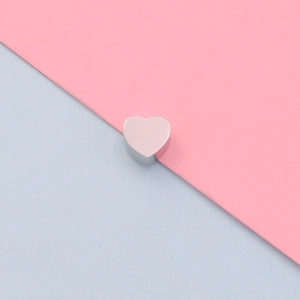 Close-up of a silver mirror-finish stainless steel heart bead for DIY jewelry making