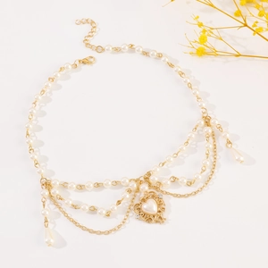 Detail of layered gold necklace with pearl tassels and rhinestone heart pendant decoration