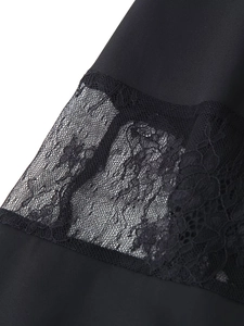 Detail of elegant black dress showing smooth fabric and intricate sheer lace stitching