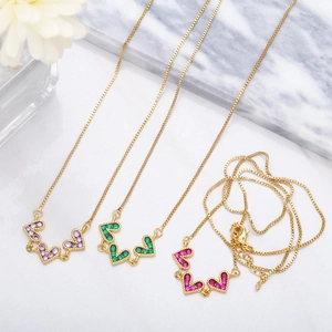 Detailed shot of gold heart pendant necklaces with lilac, emerald, and rose pink zircons