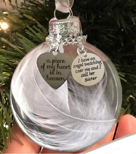 Close-up of a memorial feather ornament with heart charms on a Christmas tree