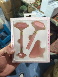 Close-up of pink quartz facial roller set in packaging with dual head roller and gua sha
