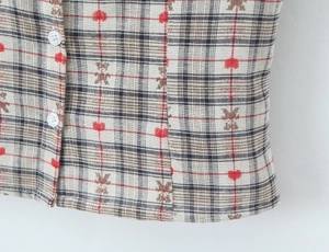 Detail of plaid shirt fabric with red heart and brown bear patterns and white buttons