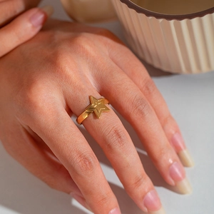 Close-up of a minimalist gold star ring with a layered star design on a female hand