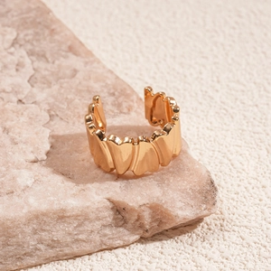 Macro detail of golden open ring with heart-shaped textures on a natural stone surface