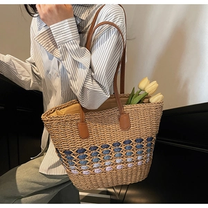 Detail of woven straw tote bag with gradient hollow pattern and brown leather straps