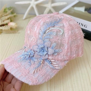 Pink lace baseball cap with floral embroidery and pearls shown in a soft setting