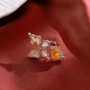 Detailed macro shot of silver flower ring with yellow gemstone on red satin background