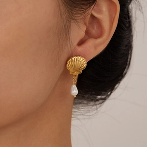 French vintage style gold plated shell earrings with pearl drops worn by a female model