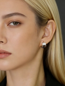 Close-up of a wide polished silver hoop earring worn on model for minimalist style