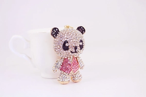 Detailed close-up of a golden panda keychain with pink vest and sparkling rhinestones