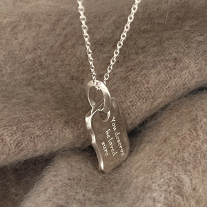 Sterling silver chain necklace with irregular engraved pendant on soft brown fabric