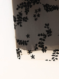 Détail du tissu en maille floquée florale noire avec doublure beige pour robe